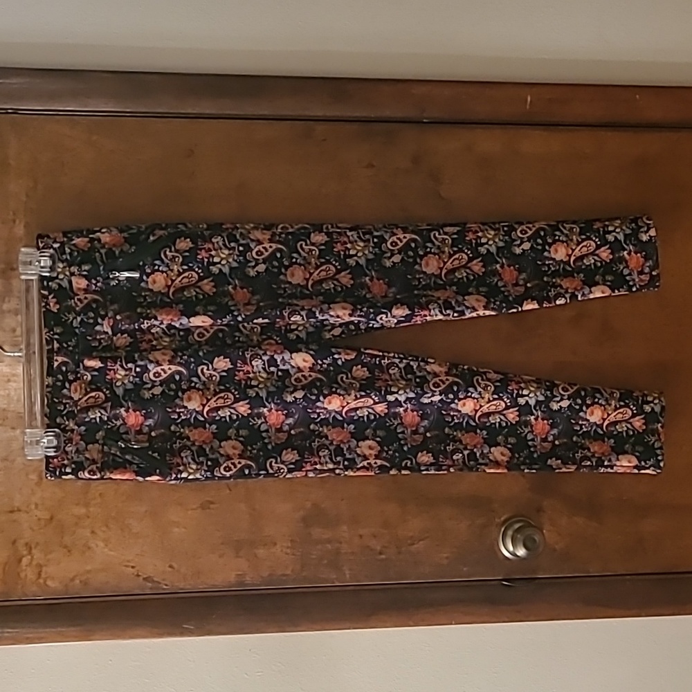 Dark blue and orange floral print leggings with pockets and zipper details.